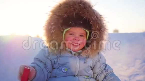 在阳光明媚的日子里快乐的孩子在冬天的公园里开心地笑着冬天的雪景户外视频的预览图