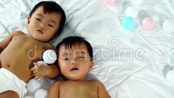 快乐的双胞胎宝宝在床上玩彩球视频的预览图