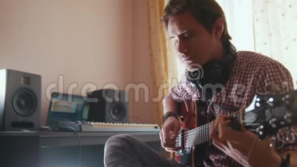 年轻的音乐家用电脑作曲并记录演奏吉他的音乐视频的预览图