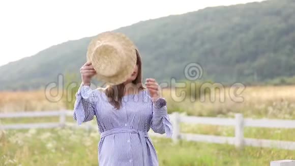 大自然中的孕妇试穿针织帽子农场附近的田野和白色农场的背景山岳山岳山岳山岳山岳视频的预览图