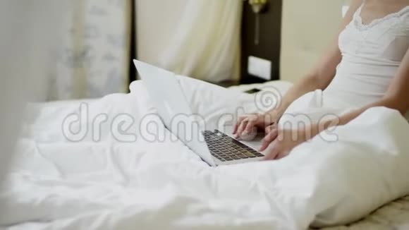 年轻女人在床上用笔记本电脑视频的预览图