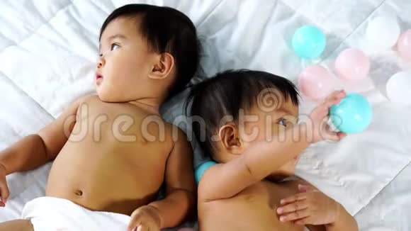 快乐的双胞胎宝宝在床上玩彩球视频的预览图