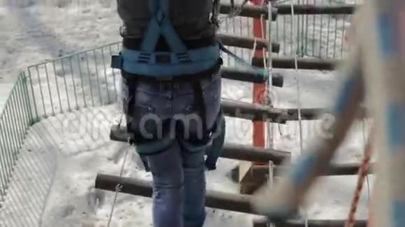 在极端公园的高绳道上年轻的女性登山者走在垂绳桥旁攀岩概念视频的预览图