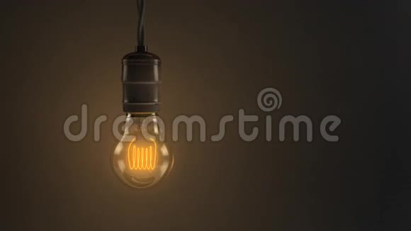 在黑暗温暖的背景上一个摇摆的老式白炽灯泡的动画循环视频的预览图