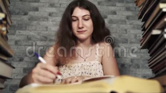 疲惫的女学生在书中读书一位身材魁梧的年轻女子坐在桌子旁手里拿着一堆书继续看书视频的预览图