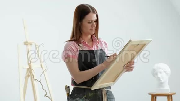 年轻美丽的女画家在画架和画布在一个明亮的工作室灵感和爱好视频的预览图