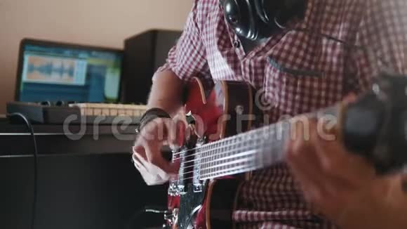 年轻的音乐家用电脑和键盘作曲并记录演奏电吉他的音乐视频的预览图