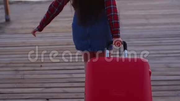 年轻女子带着手提箱在海滩上散步视频的预览图