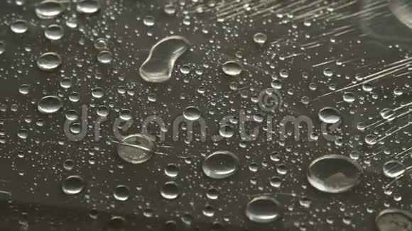 不同大小的雨滴在覆盖粘着膜的表面上的特写湿度天气和湿度概念视频的预览图