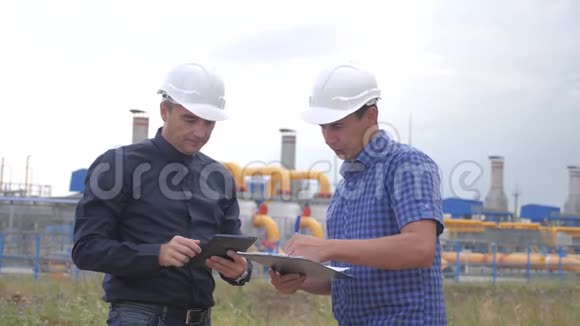 团队合作工业煤气生产站的概念慢动作视频两名戴头盔的工程师正在与视频的预览图
