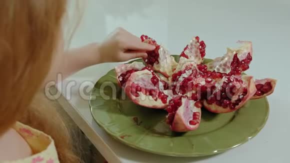 金发快乐的小女孩吃石榴健康的食物观念特写视频的预览图