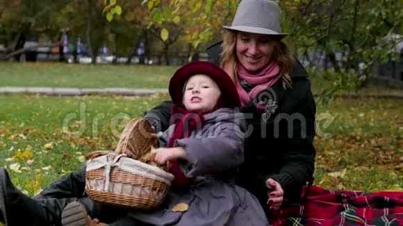 妈妈和女儿在公园里玩耍躺在地毯上扔树叶视频的预览图