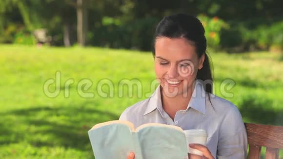 在户外喝酒读书的女人视频的预览图