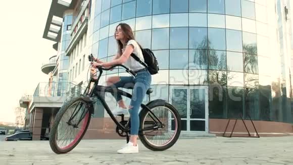 一个漂亮的女人骑着自行车在一栋4k的高楼旁视频的预览图