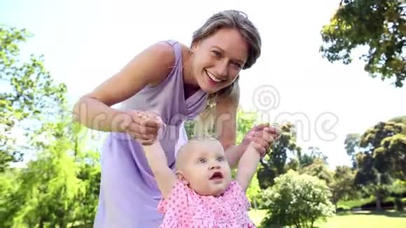 快乐的妈妈在公园里和她的宝贝女儿玩视频的预览图
