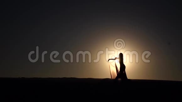 海岸上的女孩优雅地在夕阳下跳舞剪影慢动作视频的预览图