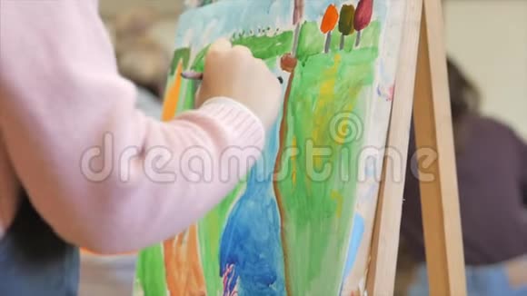 年轻的艺术家的手小女孩艺术家用画笔描绘画布坐在桌子上画画布程序视频的预览图