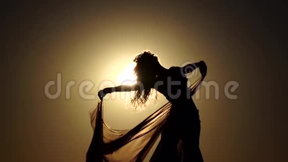 海岸上的女孩优雅地在夕阳下跳舞剪影慢动作视频的预览图