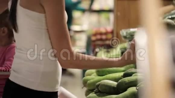 妈妈和小女儿在超市选择蔬菜的年轻家庭视频的预览图