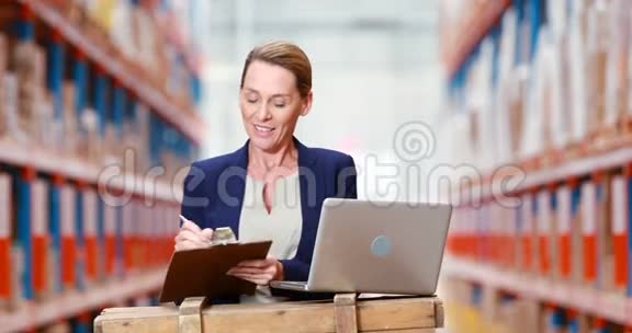 女仓库管理员在剪贴板上写字使用笔记本电脑视频的预览图