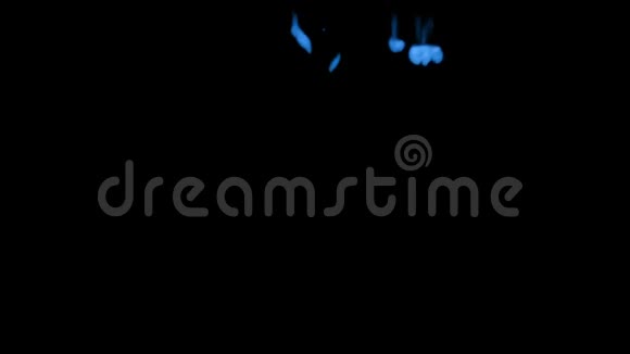 许多流动的荧光蓝墨水或烟雾隔离在黑色的缓慢运动蓝色油漆掉在水里用途视频的预览图