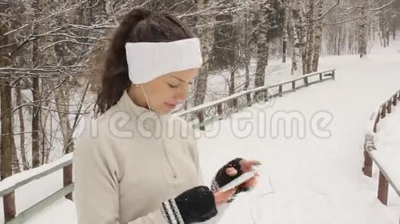 冬天年轻女子在外面听音乐和慢跑视频的预览图