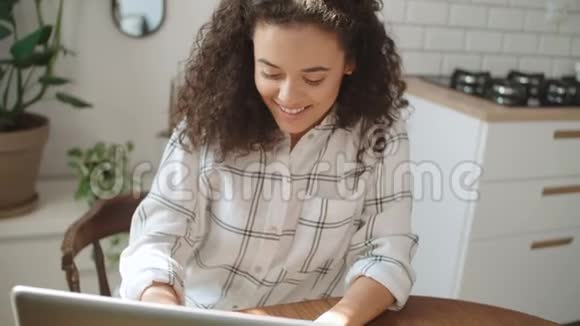 迷人的年轻女人在家里用笔记本电脑打字视频的预览图