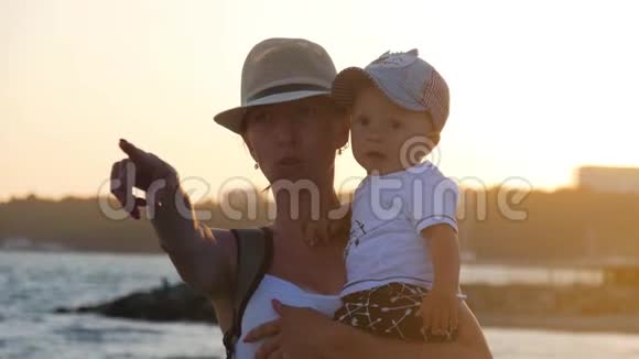 年轻的母亲把儿子抱在海边的怀里视频的预览图