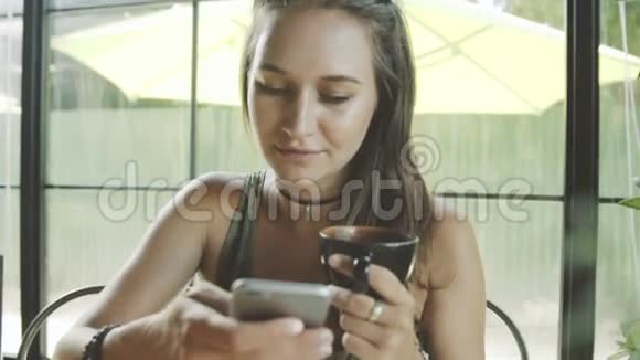 女性使用应用程序在电话和微笑在咖啡馆视频的预览图