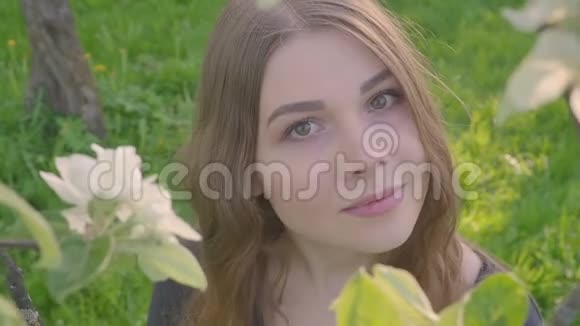 年轻快乐的女人走在苹果园里的春天花白了一位美女的肖像视频的预览图