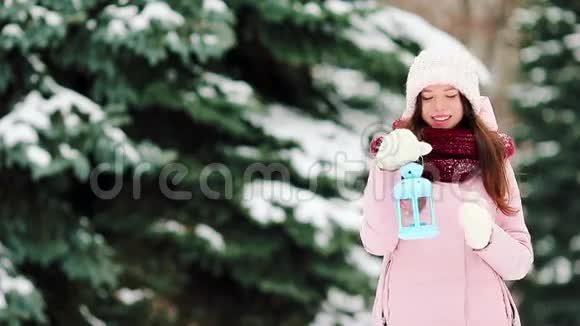 在美丽的冬日雪日年轻女子在户外举行圣诞烛光视频的预览图