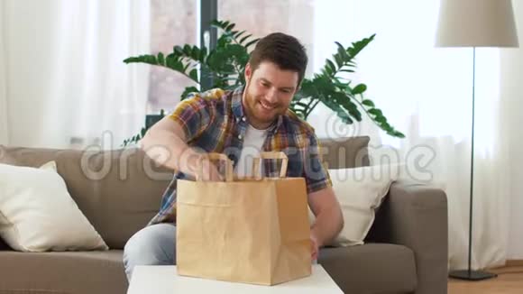 微笑的男人在家里打开外卖视频的预览图