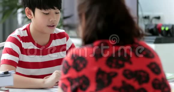 严肃的亚洲妈妈和儿子在客厅做作业视频的预览图