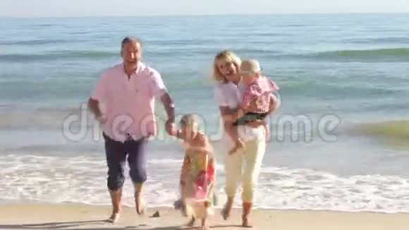 祖父母带着孙子孙女沿着海滩奔跑视频的预览图