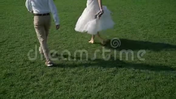 年轻的新婚夫妇在公园散步夏天新郎新娘视频的预览图