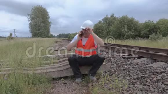 坐在铁路附近的铁路和电话视频的预览图