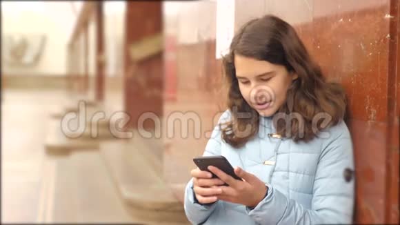 少女在地下地铁里坐地铁等待火车的到来手持智能手机的生活方式视频的预览图