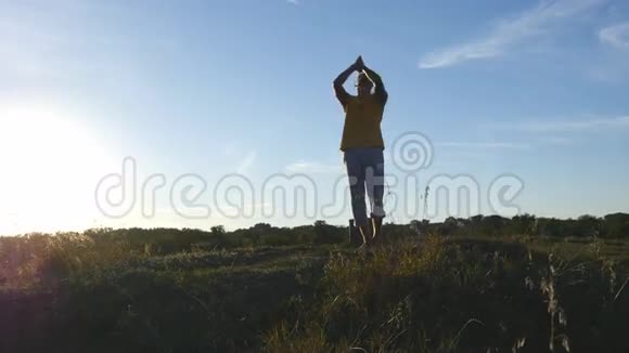 运动型男子站在户外瑜伽姿势的剪影瑜伽修行者在大自然中练习瑜伽动作和姿势美丽的视频的预览图