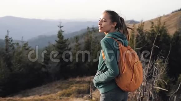 在日落的背景下站在山脊边缘的女徒步旅行者视频的预览图