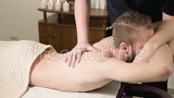 一位男性理疗师在医疗按摩室为一位男性位男性患者做伸展运动使其伸展到一位留着胡须的年轻臀部视频的预览图