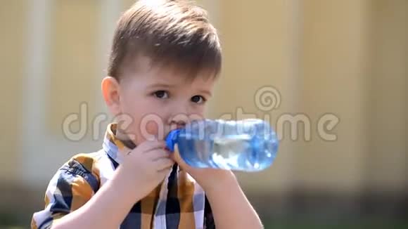 阳光明媚的一天英俊的男孩从瓶子里喝清水视频的预览图