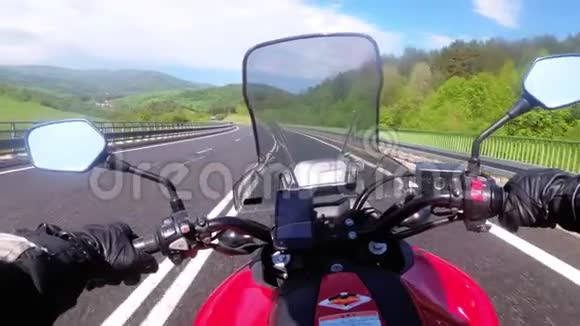 骑在空公路上的摩托车手从摩托车车轮后面看POV视频的预览图