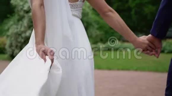 年轻的新婚夫妇在公园散步夏天新郎新娘视频的预览图