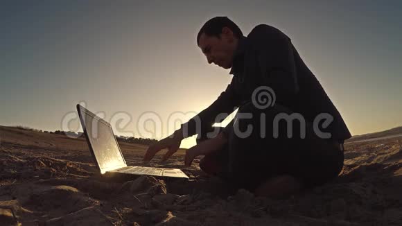 一个手提电脑商人自由职业者坐在沙滩上在阳光下自由活动视频的预览图