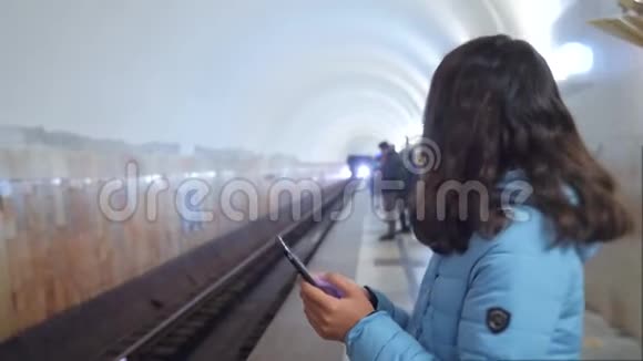 少女在地下地铁里乘地铁等待火车的到来手持智能手机一点点视频的预览图