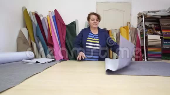 一家家具厂的一位年长妇女正在为沙发切割灰色材料视频的预览图