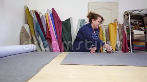 一家家具厂的一位年长妇女正在为沙发切割灰色材料视频的预览图