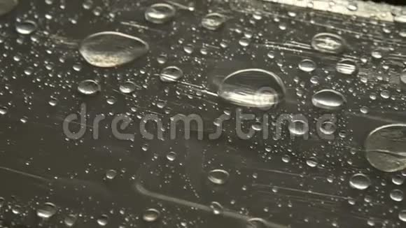 不同大小的雨滴在覆盖粘着膜的表面上的特写湿度天气和湿度概念视频的预览图