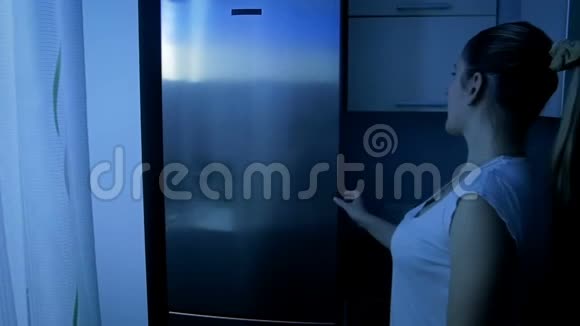 年轻微笑的女人从冰箱里拿食物视频的预览图