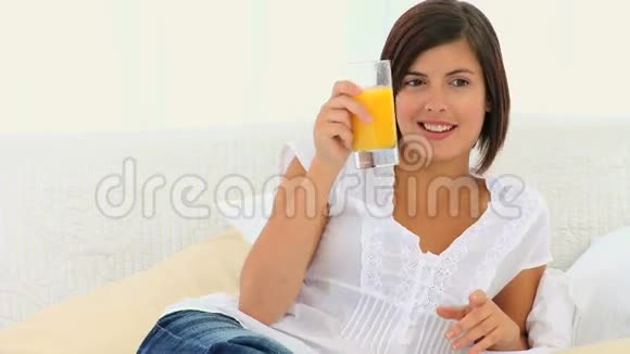 可爱的黑发女人喝着一杯橙汁视频的预览图